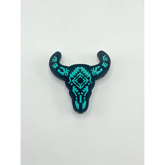 A silicone bead in the shape of a cow or bull head with teal geometric patterns.


