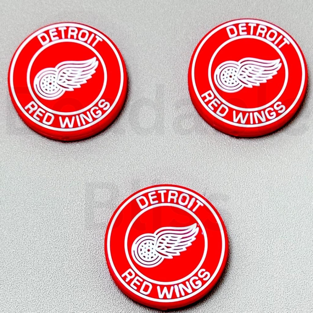 Three Detroit Red Wings logos on a gray background

