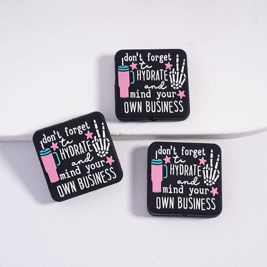 Three black coasters with humorous text design on a white surface