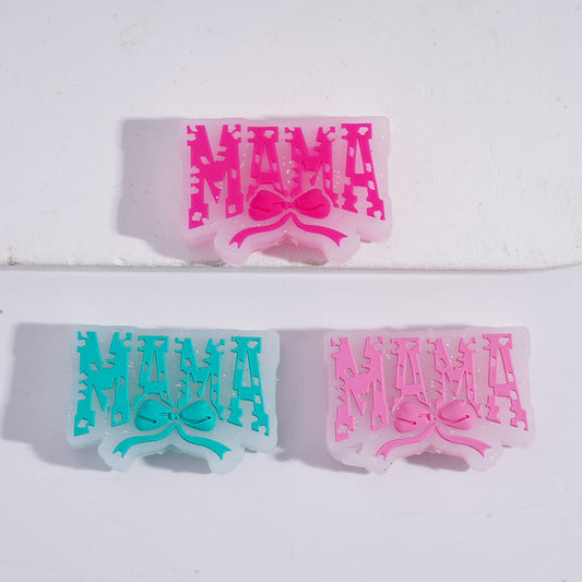 A set of silicone beads with the text 'MAMA' and a bowknot design, displayed in pink and blue colors.

