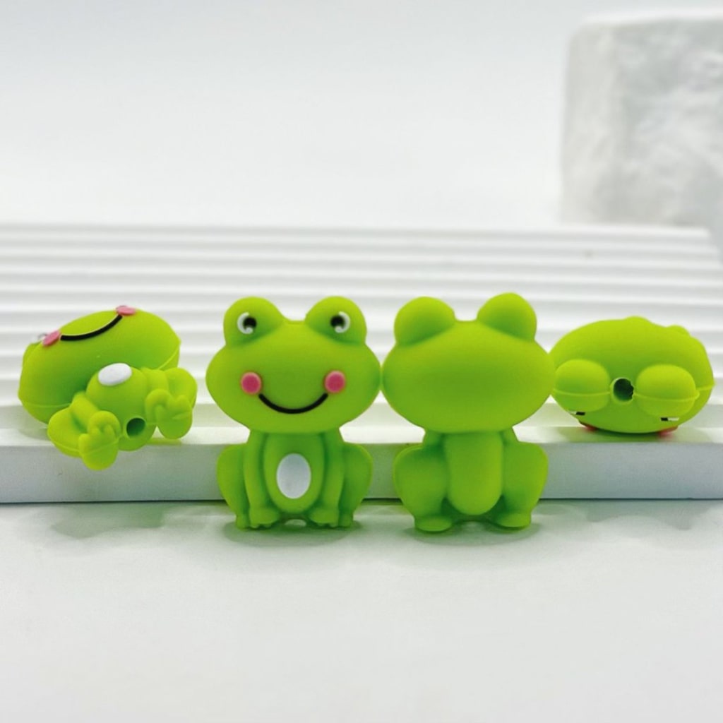 Four green frog-shaped objects with smiling faces on a white background

