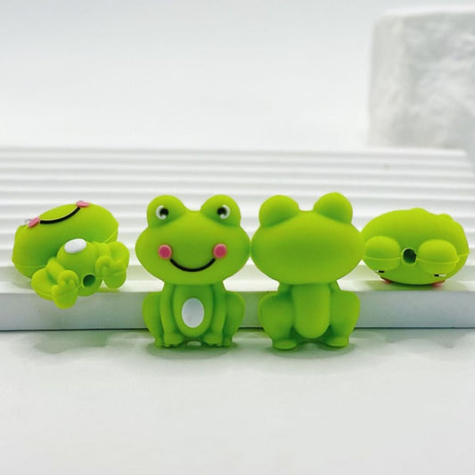 Four green frog-shaped objects with smiling faces on a white background

