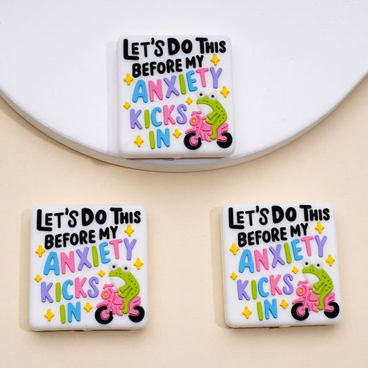 Three square silicone beads with the phrase 'Let's Do This Before My Anxiety Kicks In' and an illustration of a green frog riding a motorcycle.

