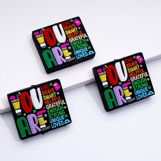 A set of rectangular silicone beads in various colors with text and形容词 printed on them, used for crafting.

