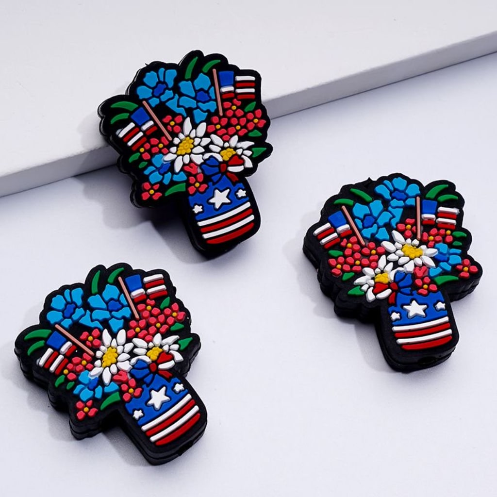 A set of silicone beads featuring a floral basket design with colors and elements indicative of the American flag.

