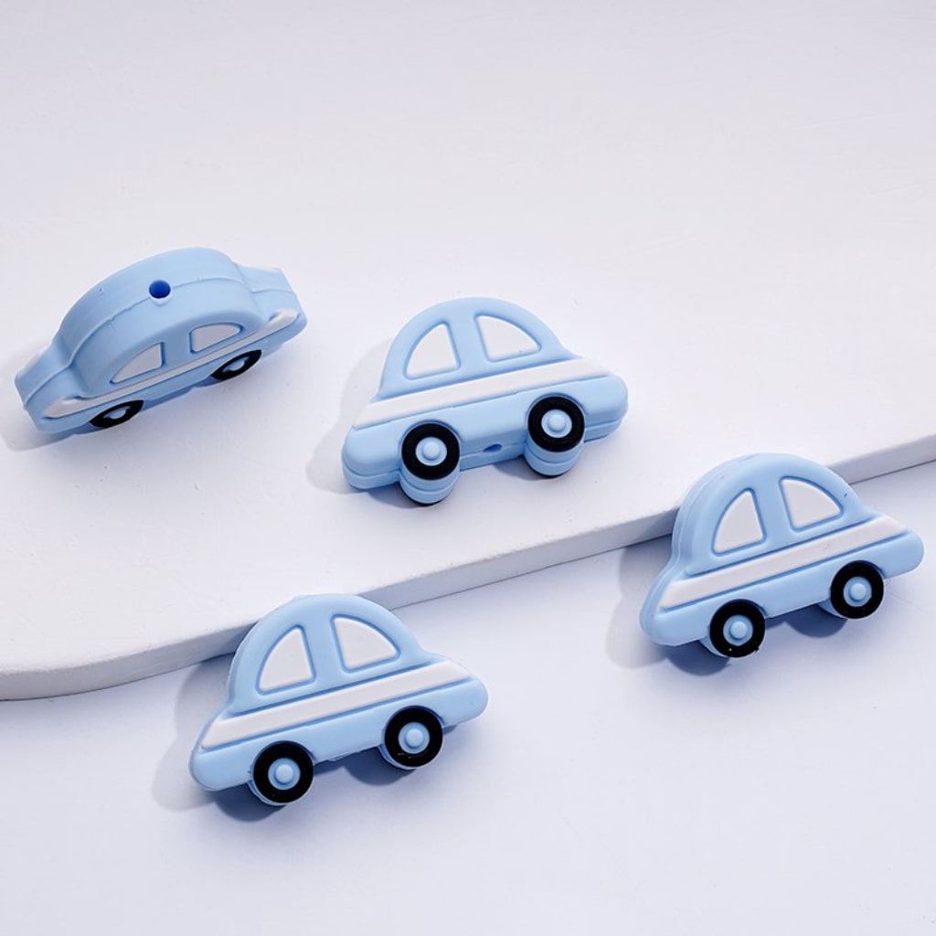 Silicone beads shaped like blue sedans, displayed on a white surface.

