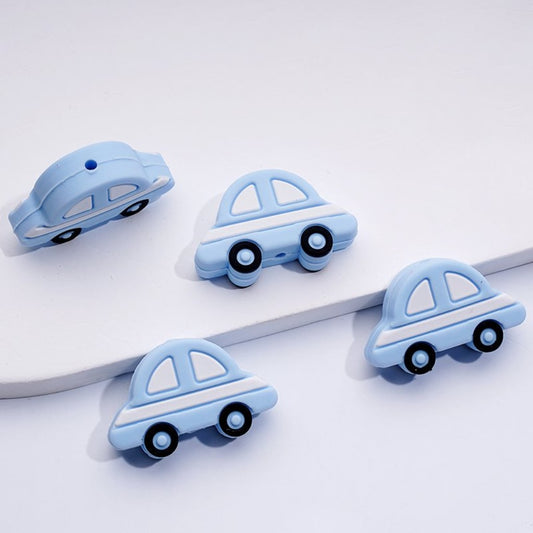 Silicone beads shaped like blue sedans, displayed on a white surface.

