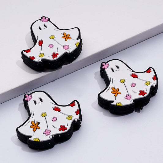 White silicone beads shaped like ghosts, decorated with colorful mini flowers, intended for Halloween crafts.


