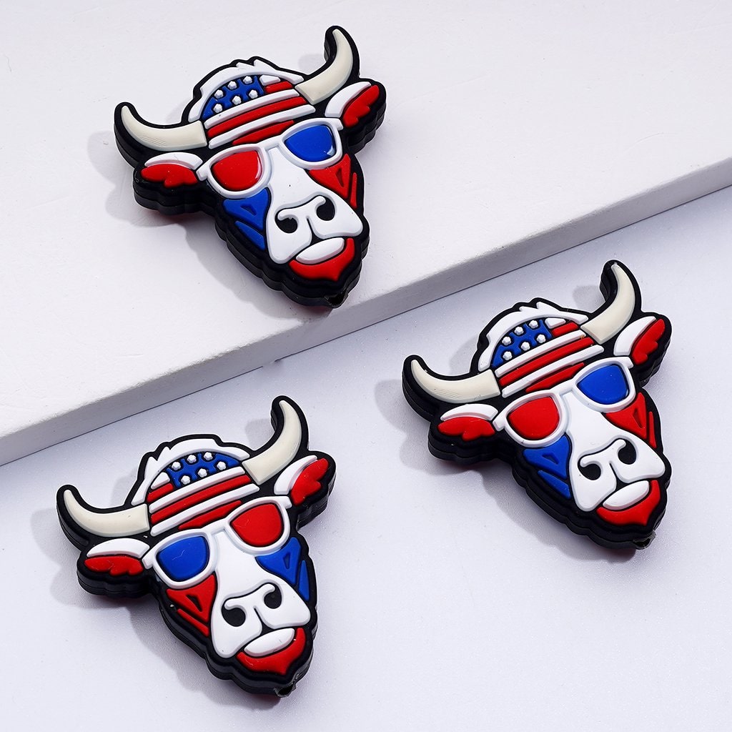 silicone beads in the shape of a cow head with a patriotic design, featuring red, white, and blue colors and glasses resembling the American flag.

