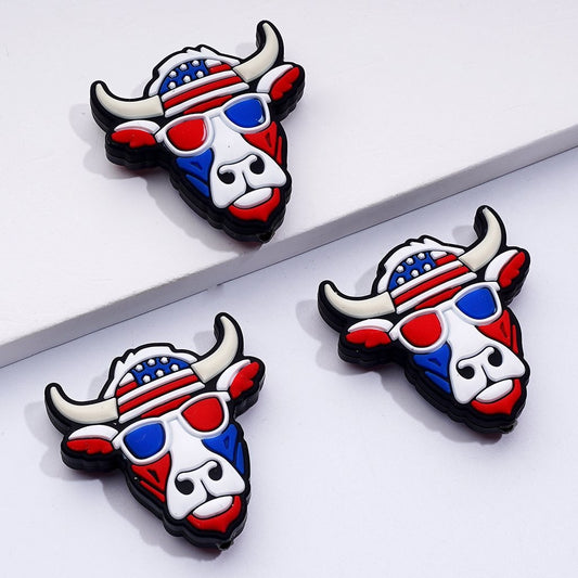 silicone beads in the shape of a cow head with a patriotic design, featuring red, white, and blue colors and glasses resembling the American flag.

