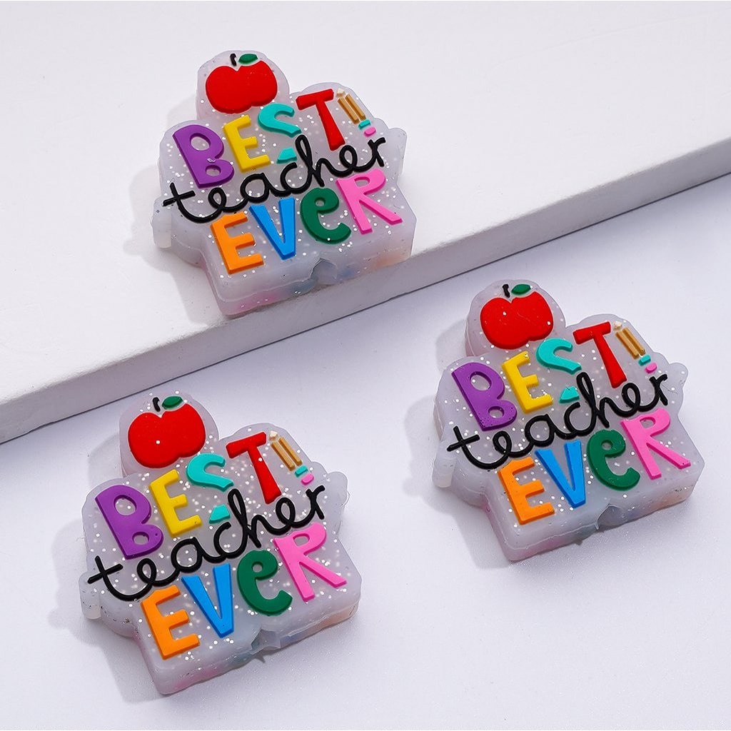 The image showcases three silicone beads, each in the shape of an apple with the phrase 'BEST Teacher EVER' written on them in colorful letters. The beads are designed to be used in crafting beadable pens.

