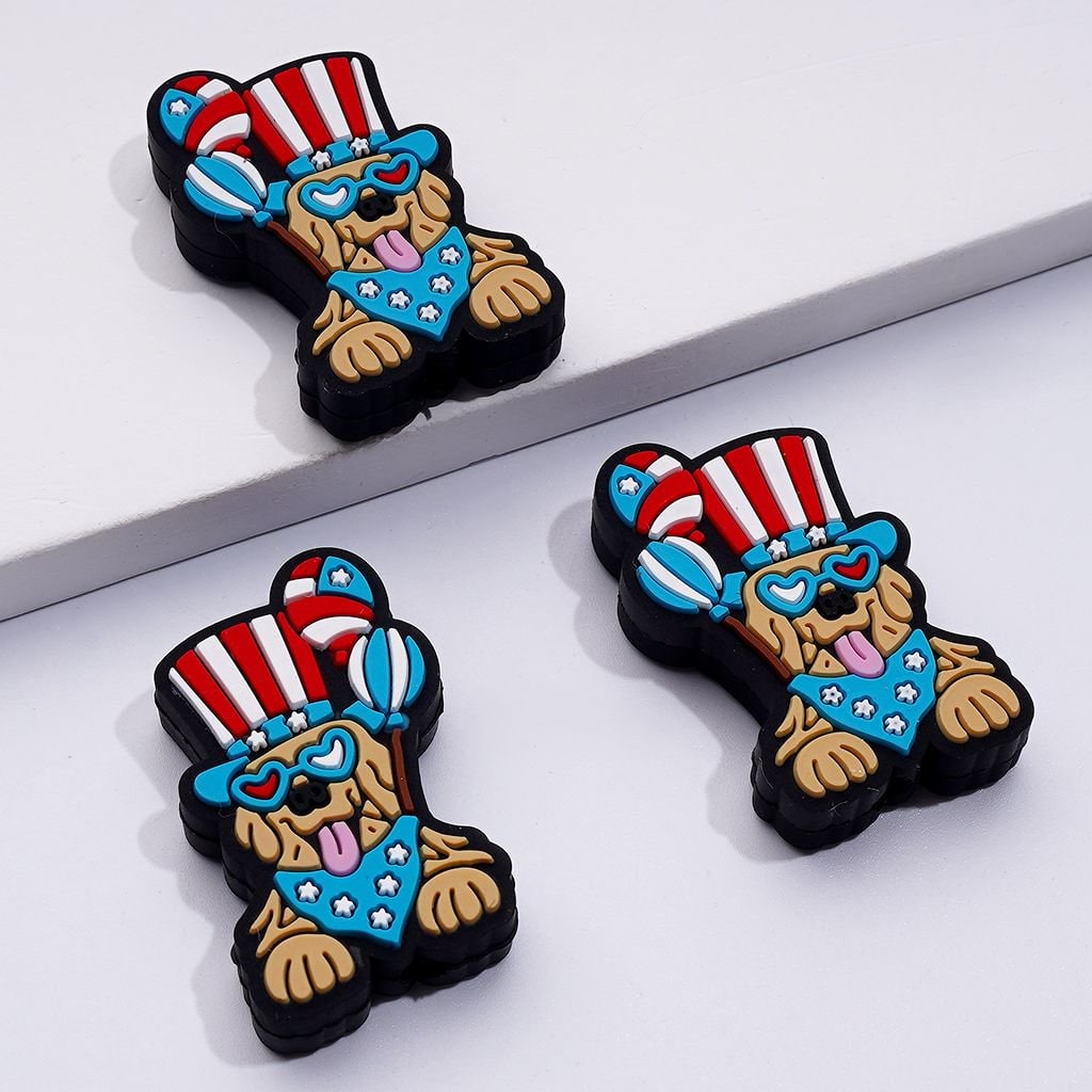 A set of silicone beads in the shape of a cute puppy dog wearing a USA flag hat, with balloons and glasses.

