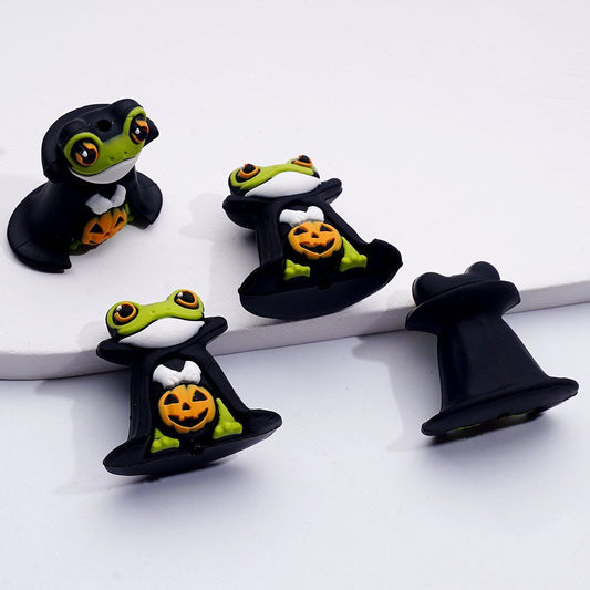 Frog-shaped Halloween decorations with black hats on a white background

