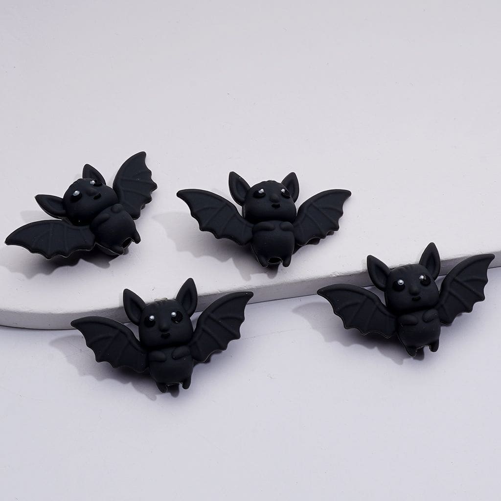 Four black bat-shaped earrings on a white background

