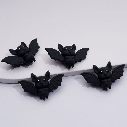 Four black bat-shaped earrings on a white background


