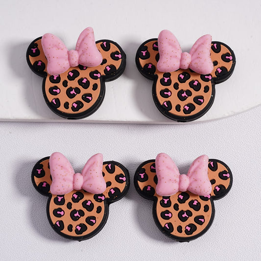 Four cookies shaped like Minnie Mouse ears with leopard print and pink bows on a white background.

