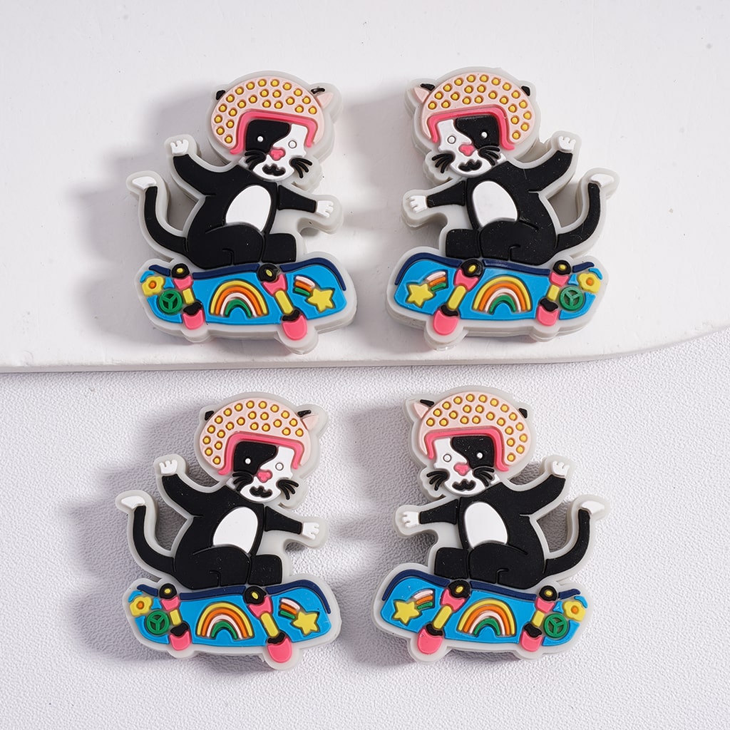 Four cat-shaped pins on skateboards with colorful designs on a white background

