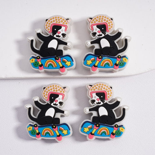 Four cat-shaped pins on skateboards with colorful designs on a white background

