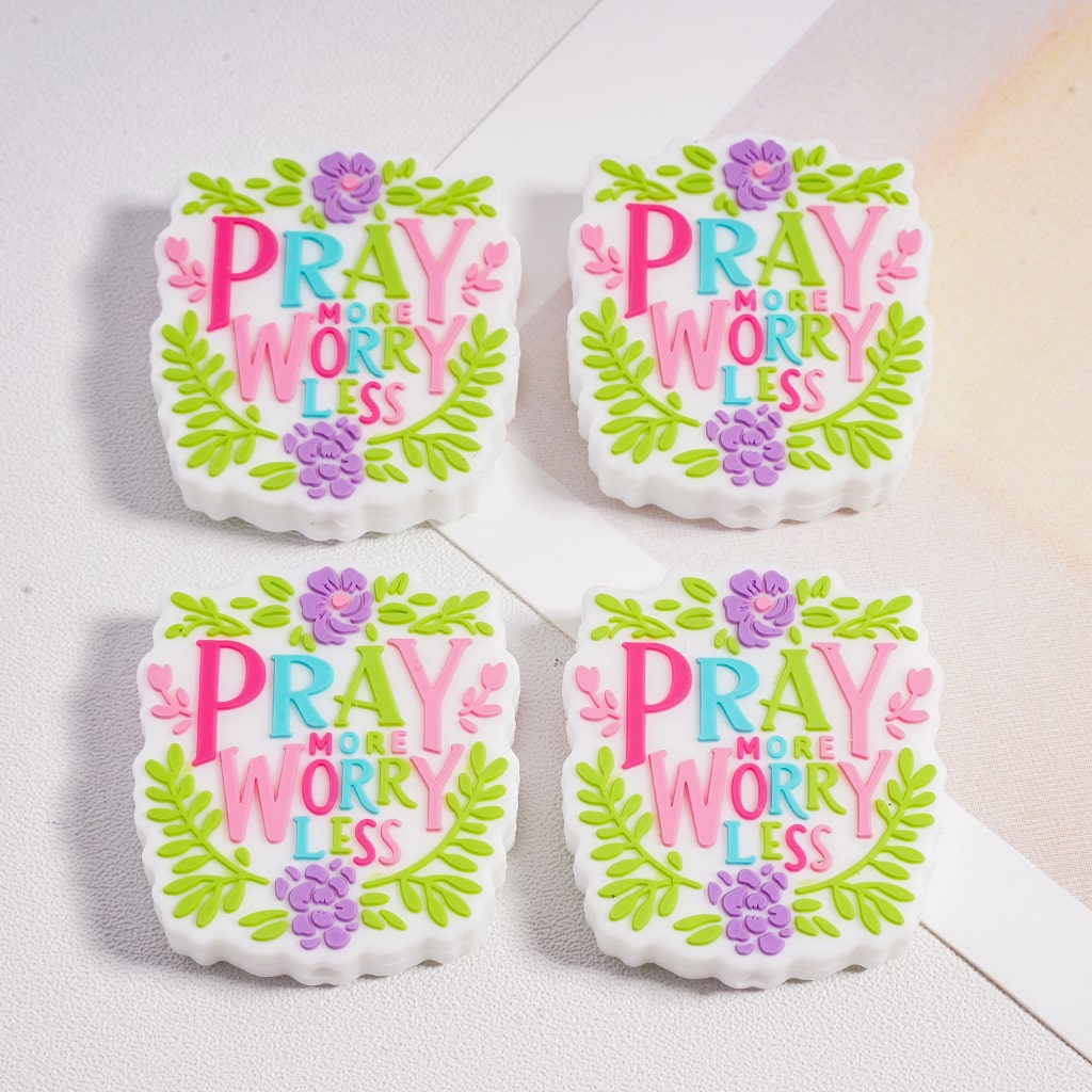 Four cookies with 'Pray More Worry Less' text and floral designs on a white surface.

