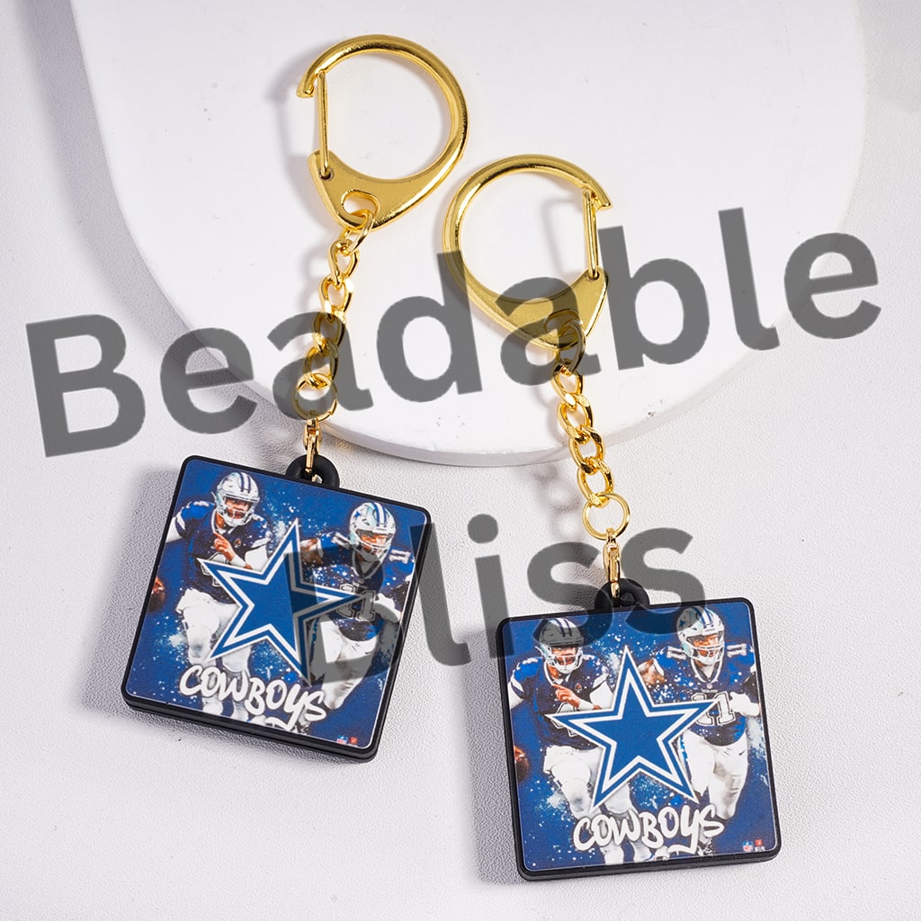 Cowboys-themed keychains with gold chains on a white background