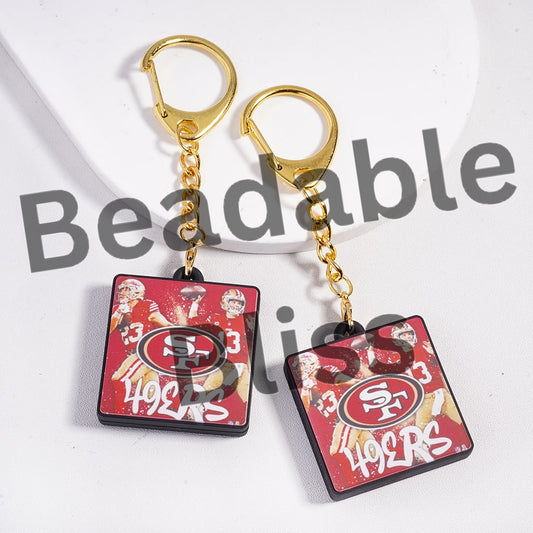 San Francisco 49ers keychains with gold chains on a white background