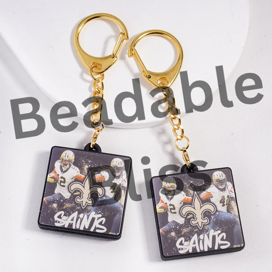 Pair of keychains with Saints logo and images on a white background