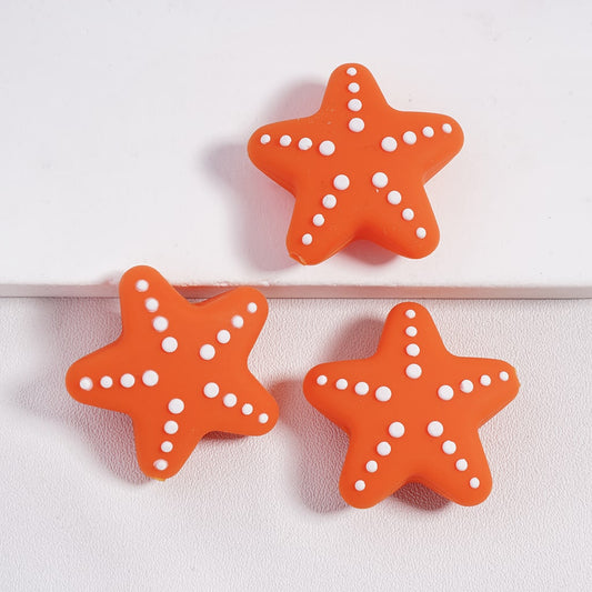 Three orange starfish-shaped objects with white polka dots on a light pink background