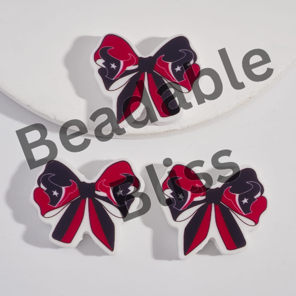 Bow-shaped earrings with red, black, and white design on a light gray background.