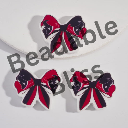 Bow-shaped earrings with red, black, and white design on a light gray background.