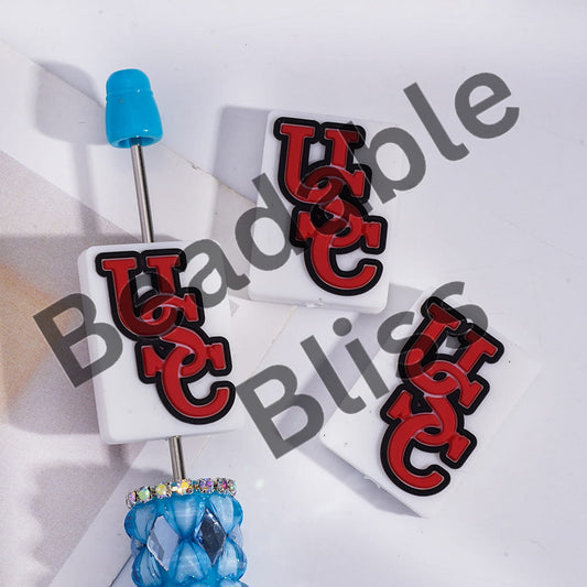 White lip gloss with red 'USC' logo on a white background, featuring 'handsonsupply.com'.