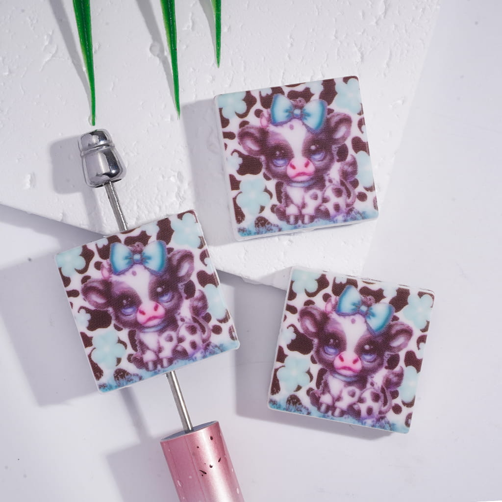 Two square keychains with a cartoon character design on a white background

