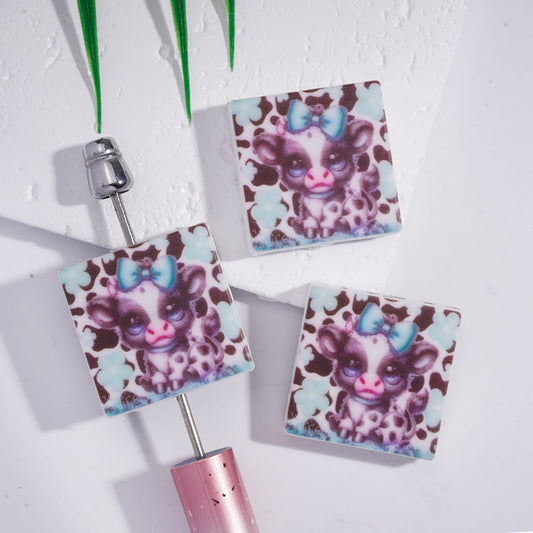 Two square keychains with a cartoon character design on a white background

