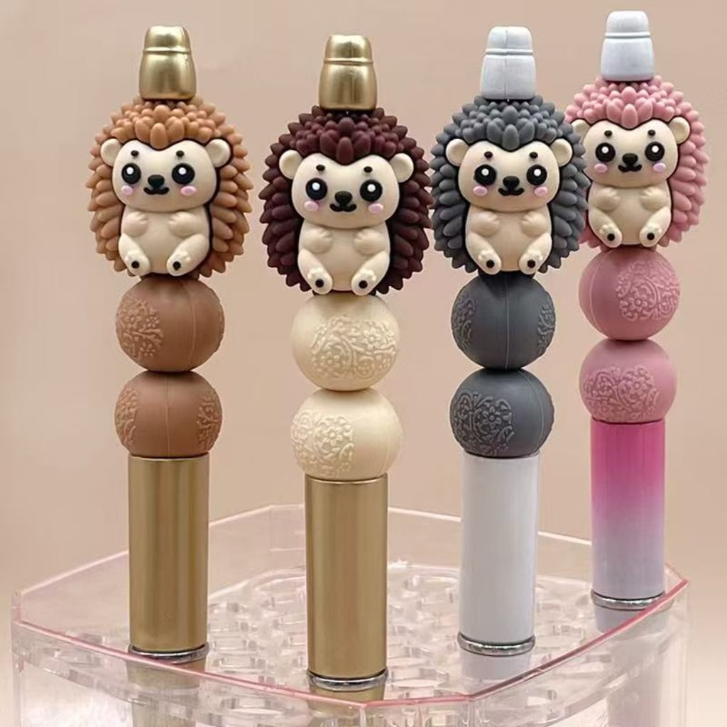 A collection of silicone beads designed to look like hedgehogs, in various colors, attached to pen-style writing instruments.

