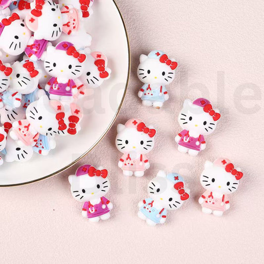Hello Kitty-themed resin charms on a pink surface with a white plate.

