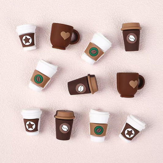 Set of toy coffee cups with various designs on a light pink background

