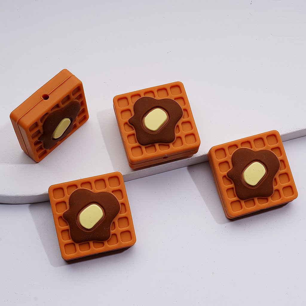 Four square-shaped waffle cookies with a heart-shaped chocolate center on a white background

