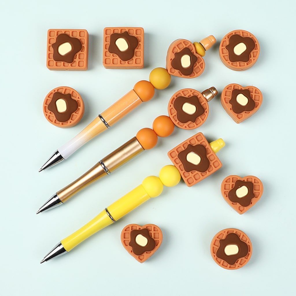 Three pens with waffle-themed pen caps on a light blue background

