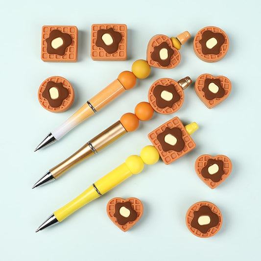 Three pens with waffle-themed pen caps on a light blue background


