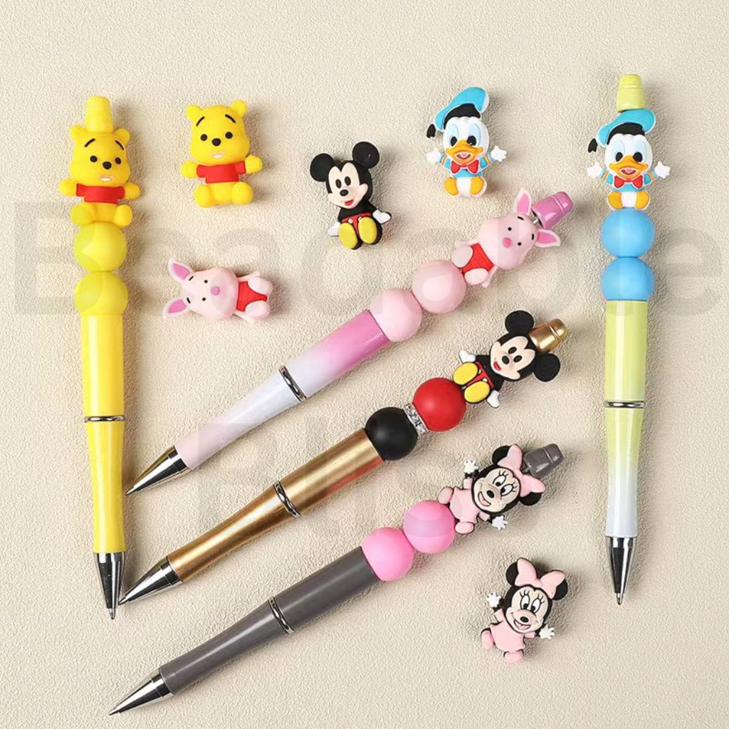 Set of cartoon character pens and charms on a beige background

