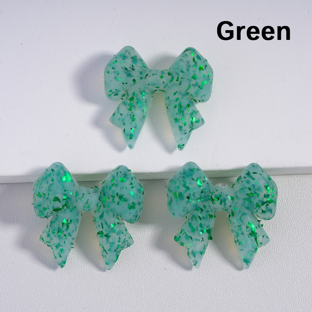 Green glittery bow-shaped earrings on a white background

