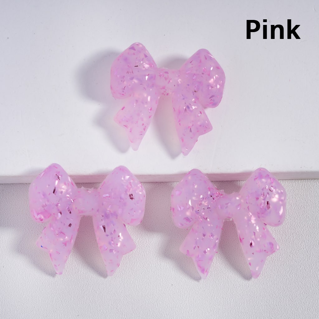 Pink glittery bow-shaped earrings on a white background

