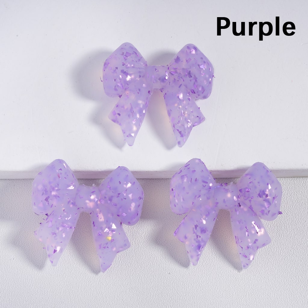 Purple glittery bow-shaped earrings on a white background

