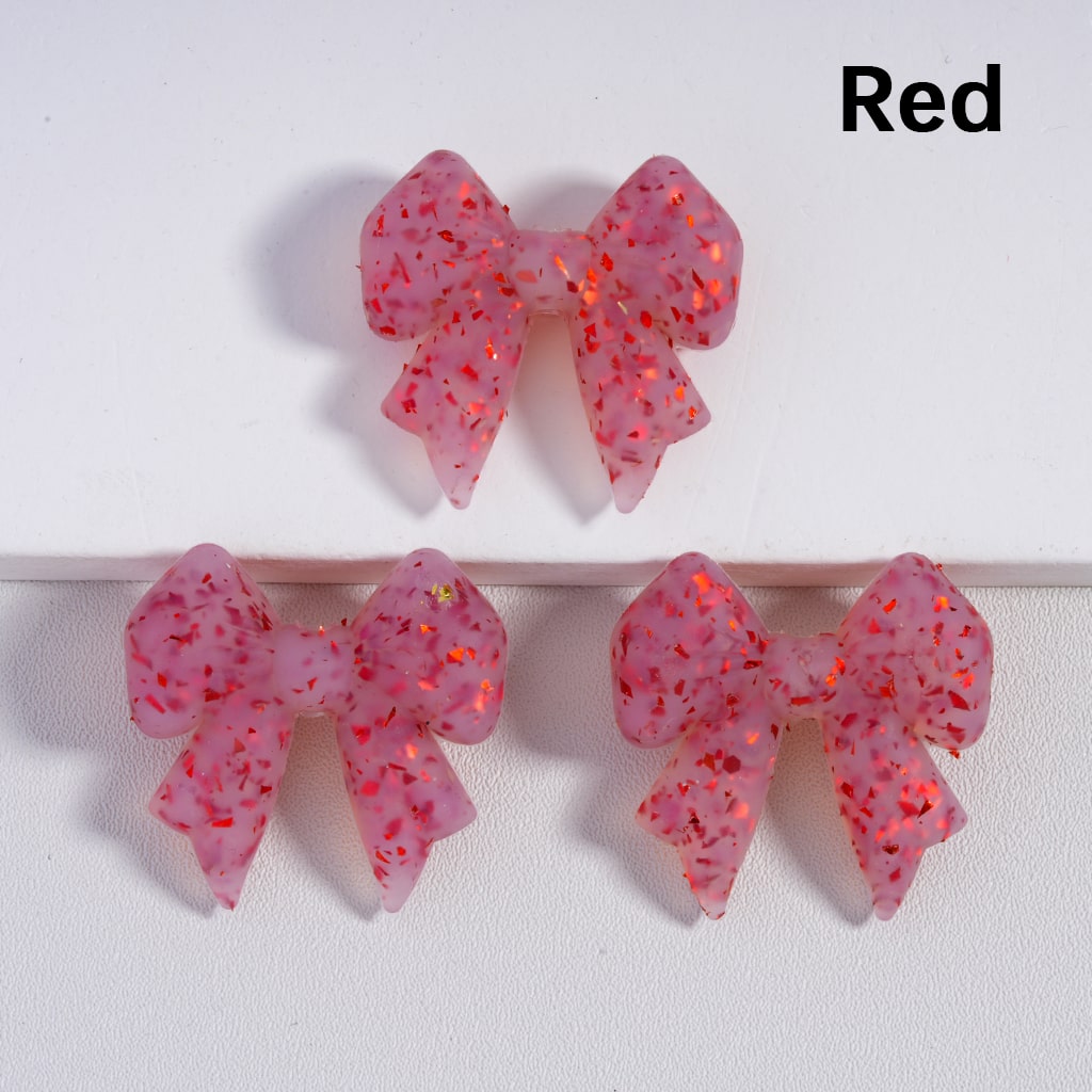 Pink glittery bow-shaped earrings on a white background with 'Red' text.

