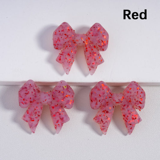 Pink glittery bow-shaped earrings on a white background with 'Red' text.

