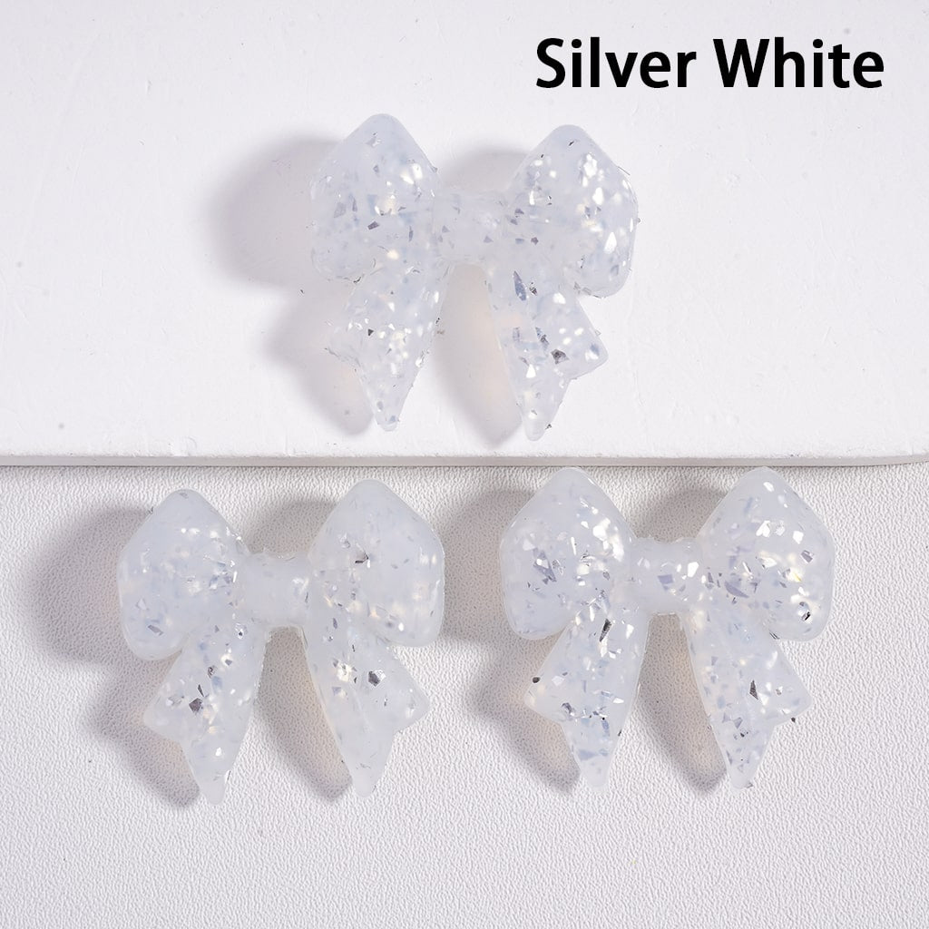Silver white bow-shaped earrings on a light gray background

