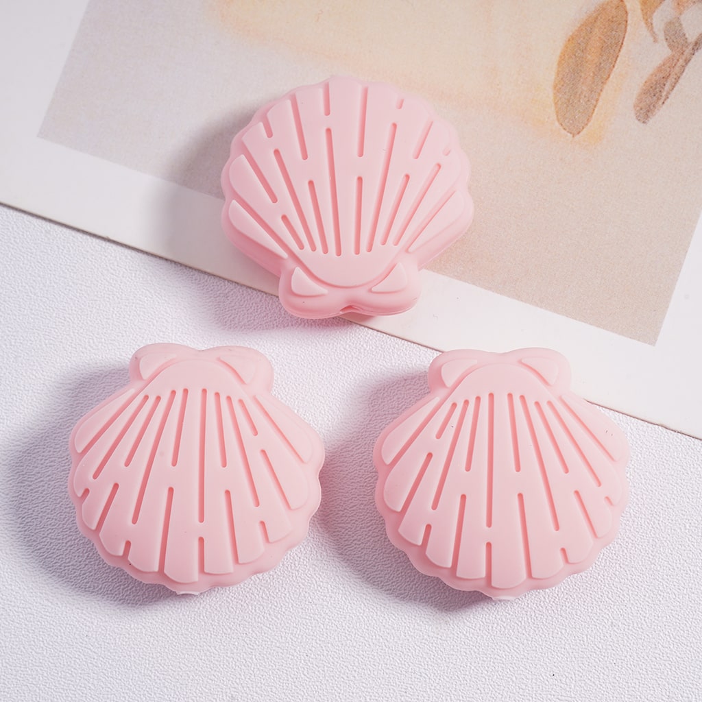 Three pink shell-shaped objects on a light background

