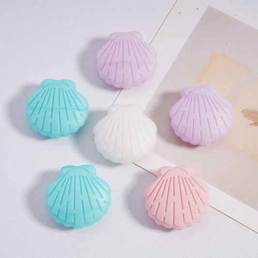 Shell-shaped bath bombs in pastel colors on a light surface.

