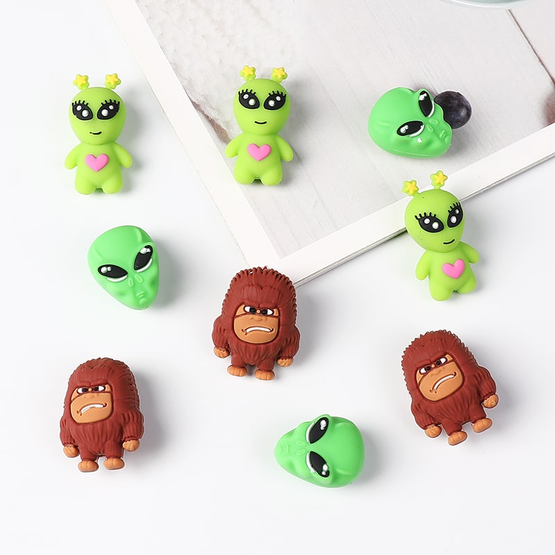 Set of green alien and brown orangutan figurines on a white surface.

