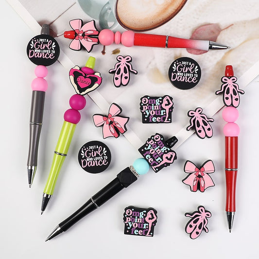 A collection of pens and pencils with silicone beads in the shapes of pink bowknots and hearts attached to them, with the phrase 'GIRL POWER' written on one of the pens.

