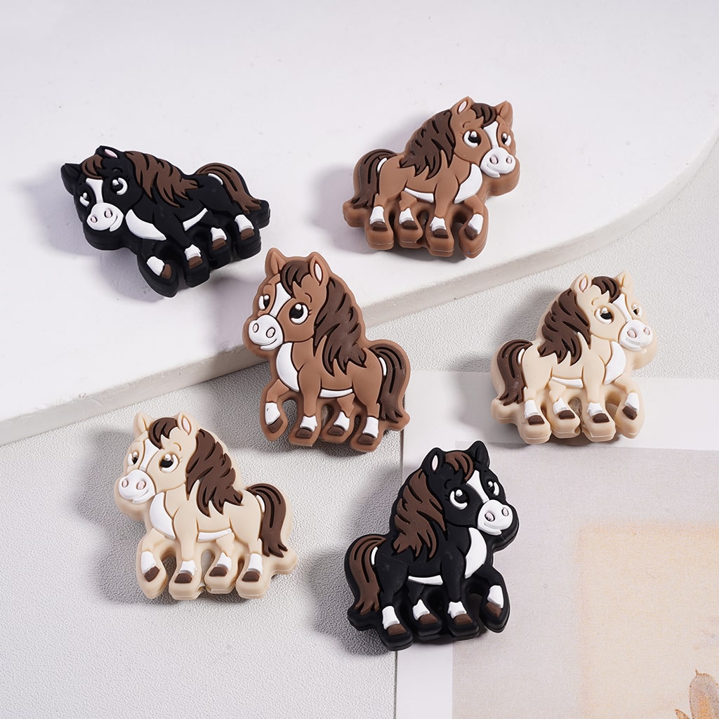 Set of six horse-shaped hair clips on a white surface


